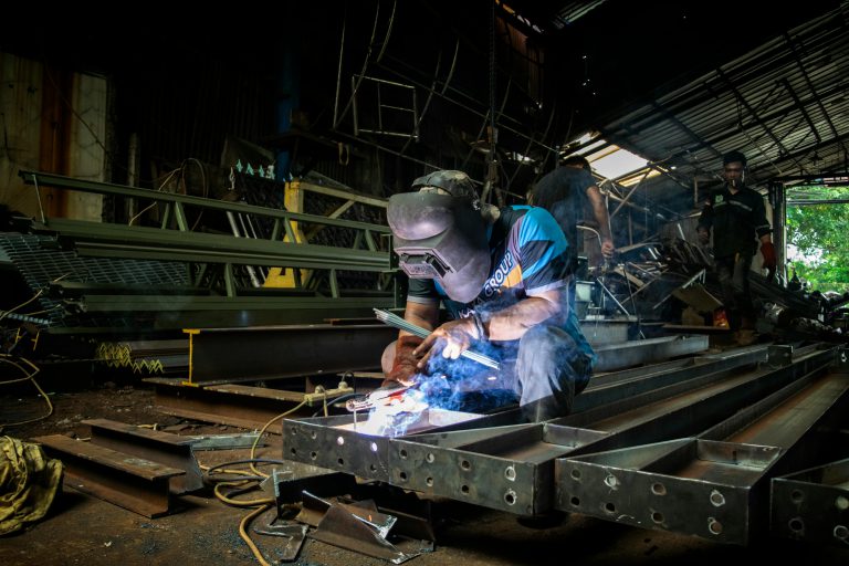Pracownicy wykonujący produkcja wyrobów metalowych toruń w ciemnym magazynie