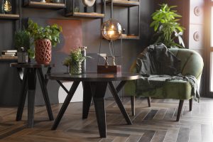 Nowoczesny salon z ciemnym stołem, zielonym fotelem i roślinami – meble stylowe w przytulnym wnętrzu