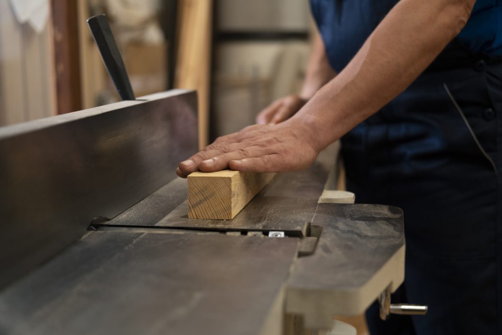 Producent łóżek drewnianych obrabiający element z litego drewna podczas przygotowania konstrukcji łóżka